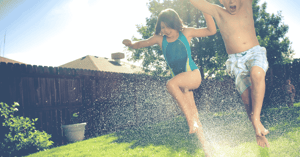 Kids jumping through sprinklers