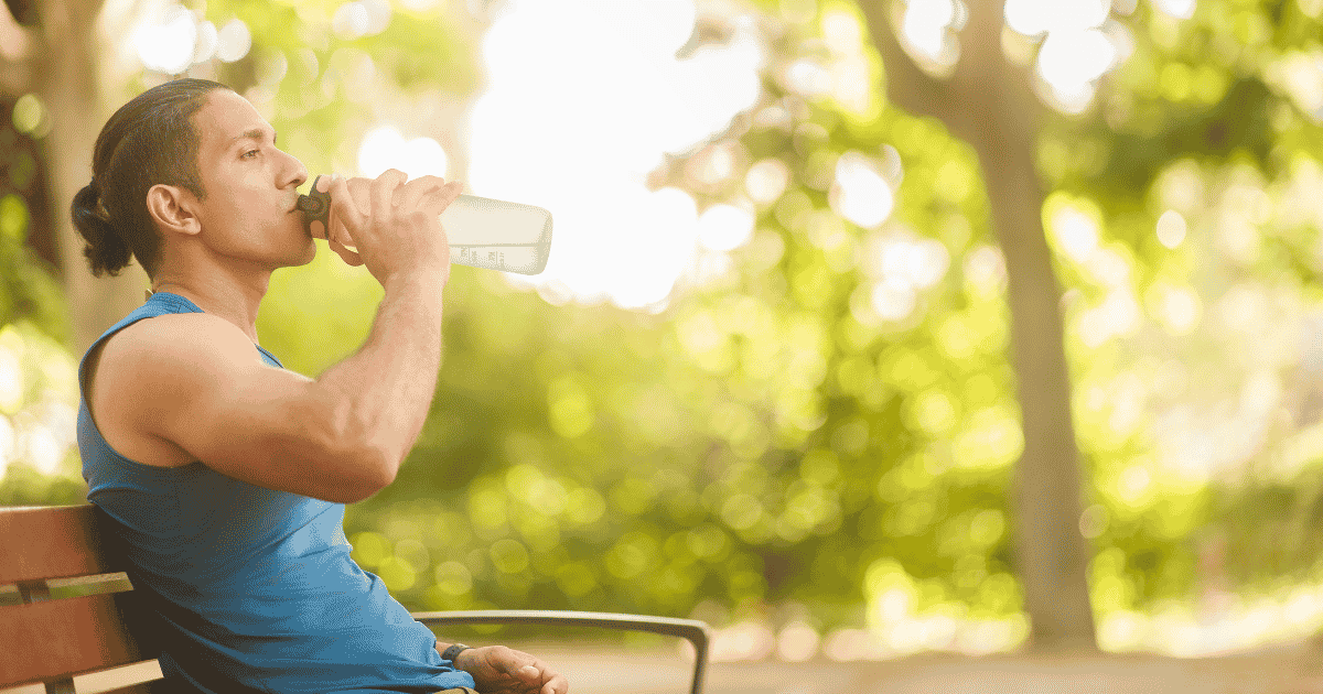 Man on a bench drinking water