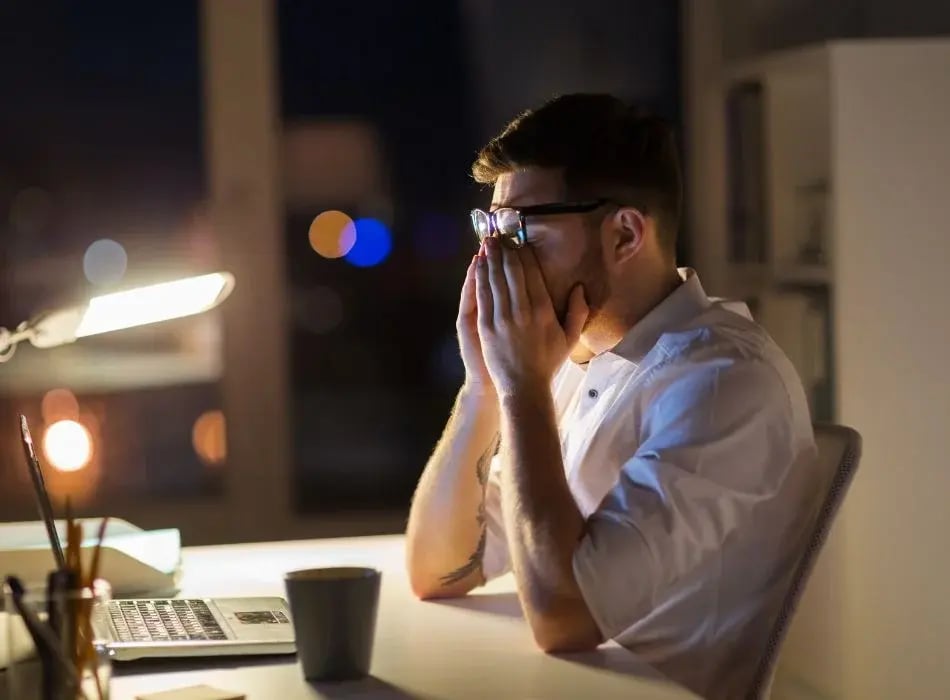 man at desk rubbing eyes